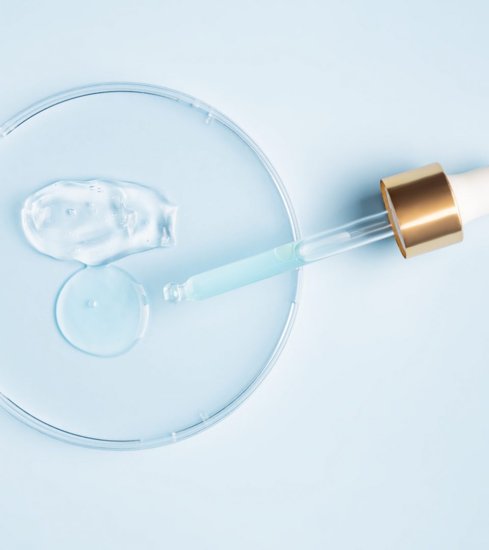 smear of cosmetic gel stroke and round transparent drop of serum in a petri dish on a blue background. Concept laboratory tests and research, making and testing cosmetic